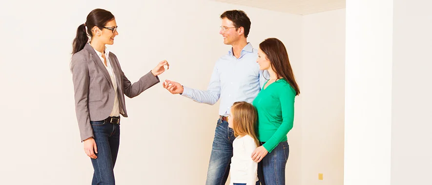 family of three receives keys to their new home from their realtor