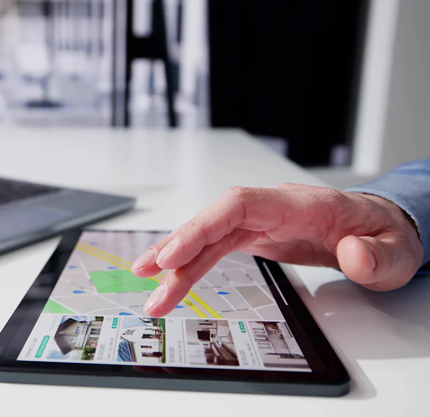 close up image of a man using a tablet, scrolling through home listings